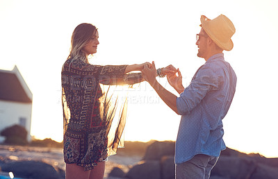 Buy stock photo Shot of an affectionate young couple holding hands at the beach