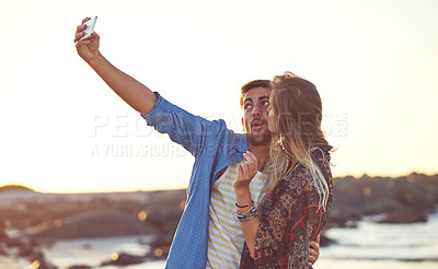 Buy stock photo Shot of an happy young couple taking selfies at the beach