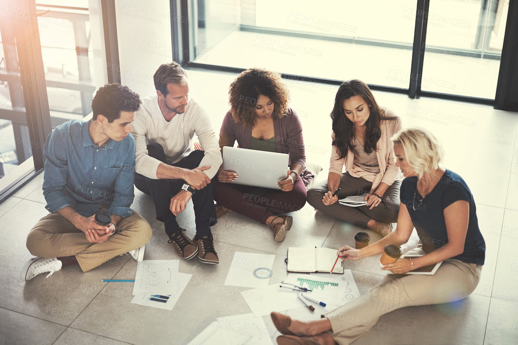 Buy stock photo Shot of a team of designers brainstorming on the floor in an office