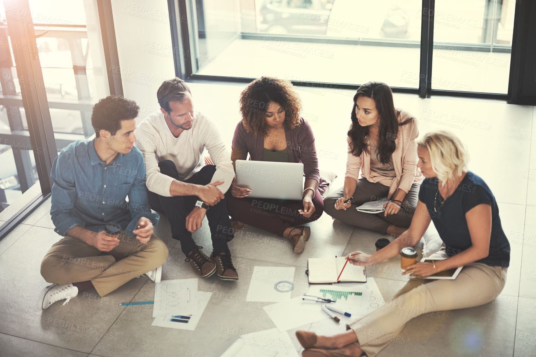 Buy stock photo Shot of a team of designers brainstorming on the floor in an office