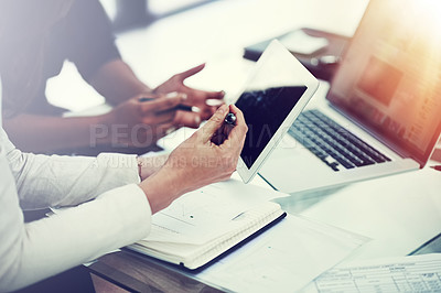 Buy stock photo Cropped shot of two colleagues using a digital tablet together during a collaboration at work