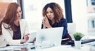 Buy stock photo Shot of two businesswomen using a digital tablet together during a collaboration at work