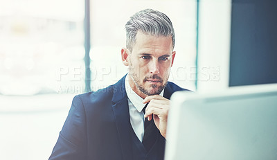 Buy stock photo Shot of a mature businessman using a computer at his desk in a modern office