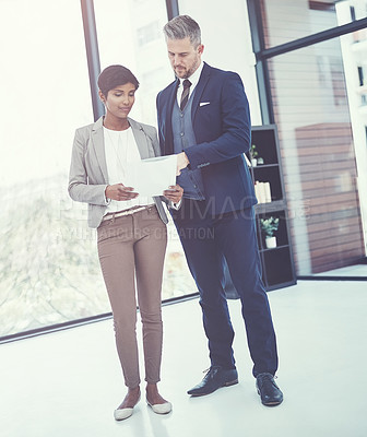 Buy stock photo Shot of a businesswoman and businessman reading a document together at work