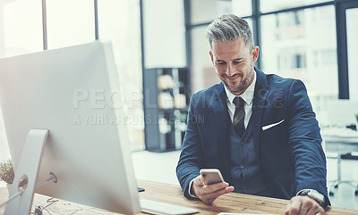 Buy stock photo Shot of a mature businessman using a cellphone at his desk in a modern office