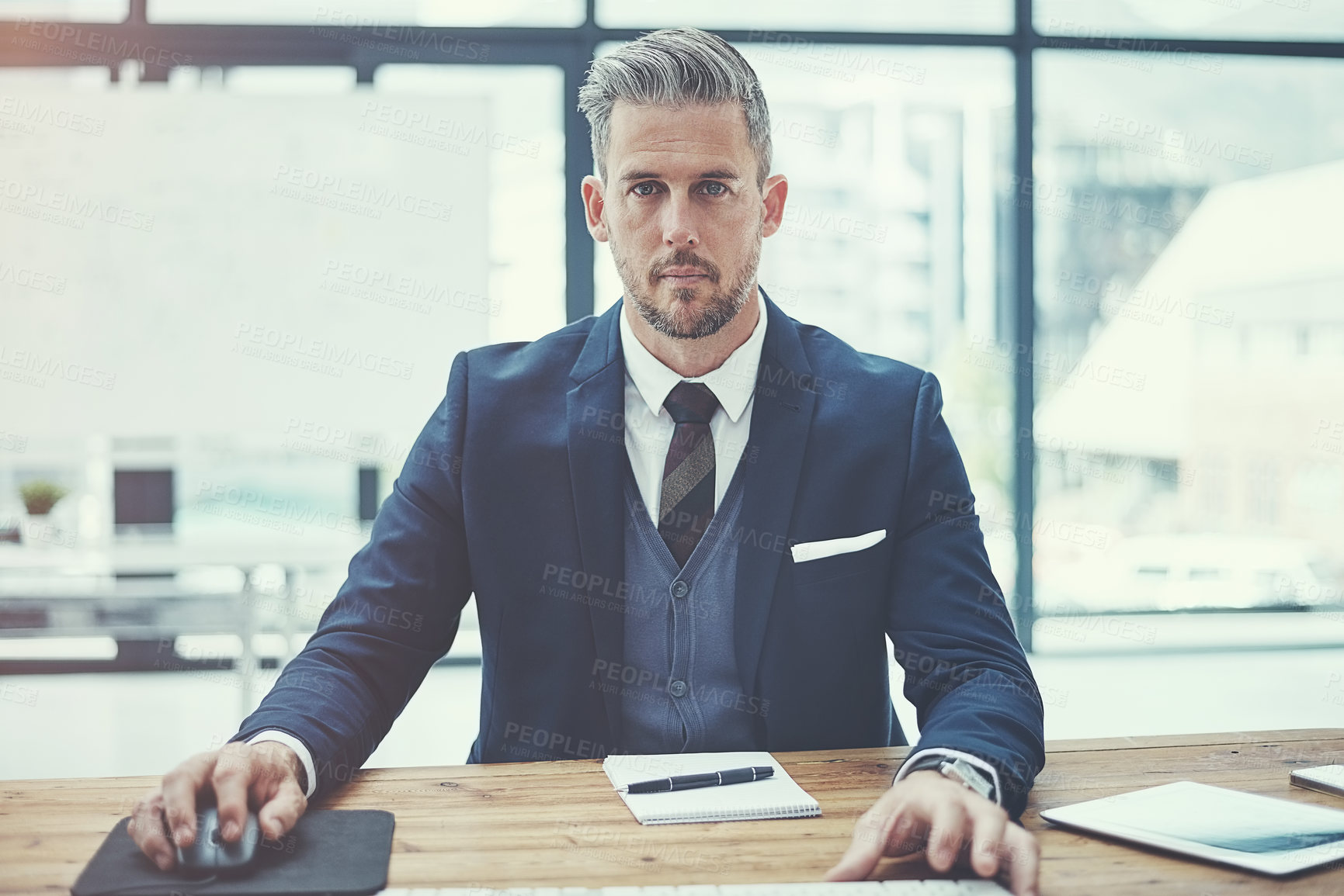 Buy stock photo Portrait of a mature businessman using a computer at his desk in a modern office