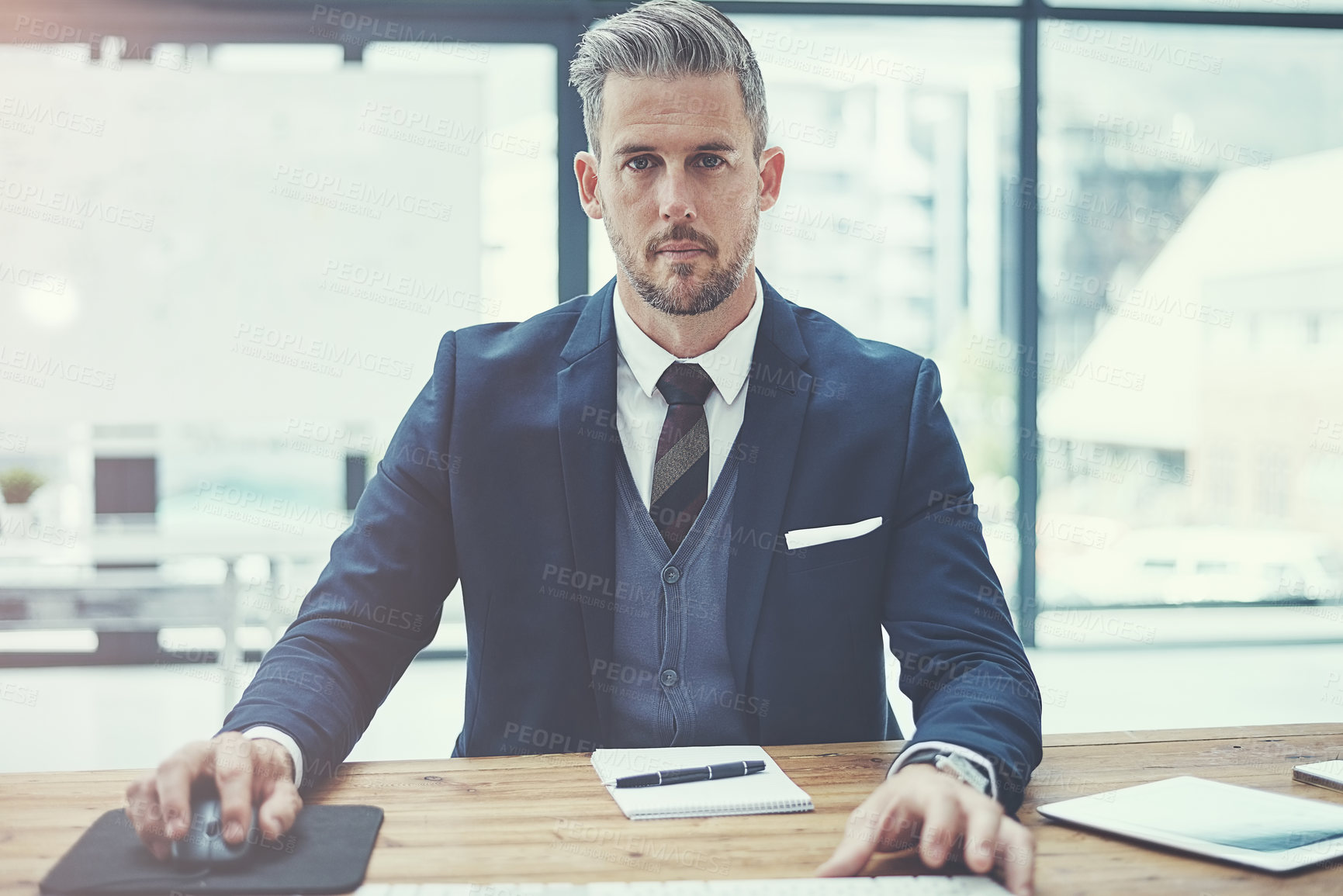 Buy stock photo Portrait of a mature businessman using a computer at his desk in a modern office