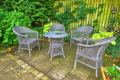 Buy stock photo Chairs around a table in a garden terrace on a bright and sunny day. Rustic outdoor furniture to relax and have a picnic at while enjoying the fresh spring air. Comfortable seating in nature