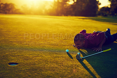 Buy stock photo Shot of a young man eyeing up the putt during a round of golf