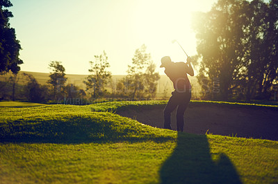Buy stock photo Shot of a young man hitting the ball out of the bunker during a round of golf
