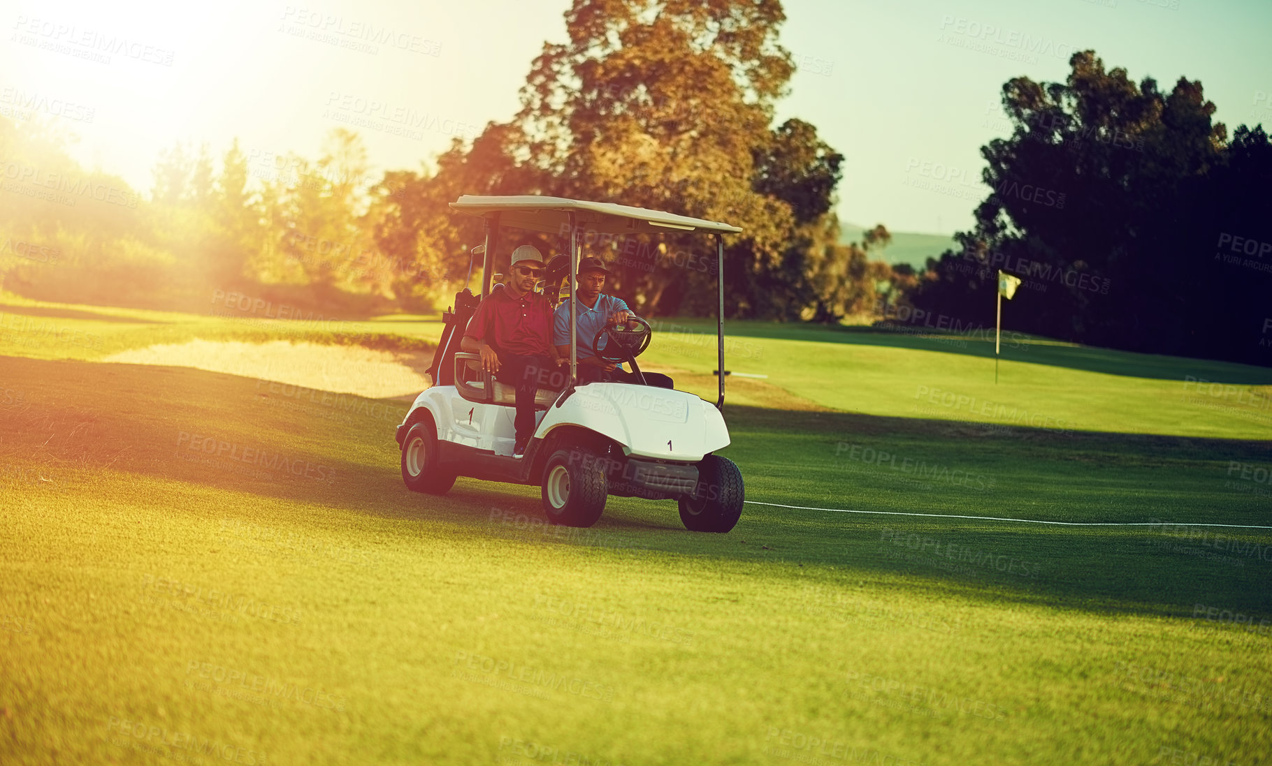 Buy stock photo Shot of two golfers riding in a cart on a golf course