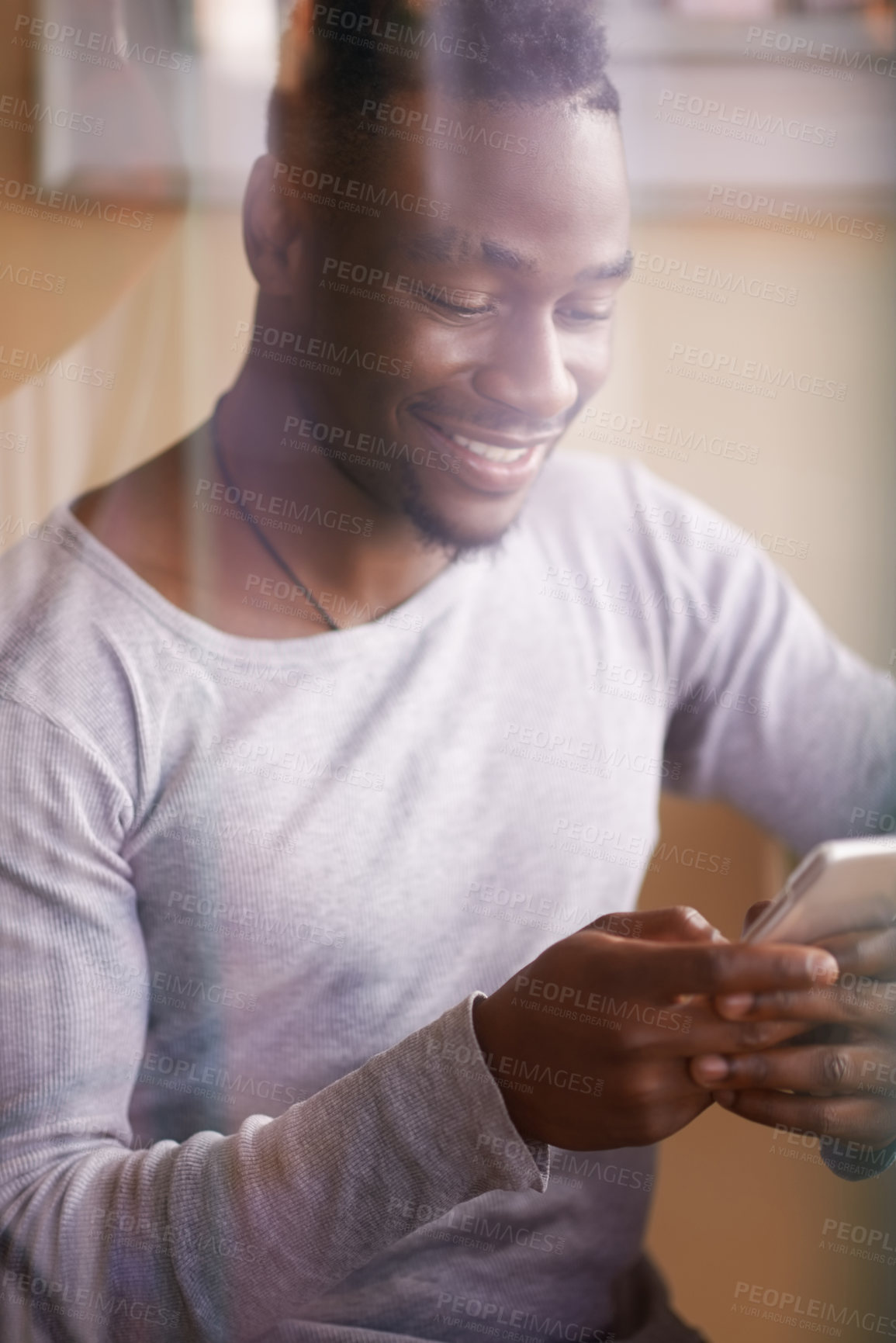 Buy stock photo Cropped shot of a handsome young man using his phone while sitting in a cafe