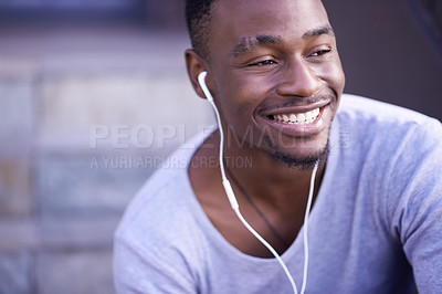 Buy stock photo Shot of a young man listening to music while sitting on a staircase outside
