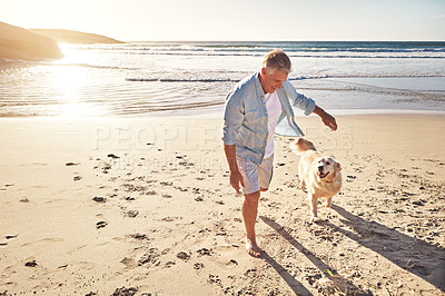 Buy stock photo Shot of a mature man taking his dog for a walk on the beach