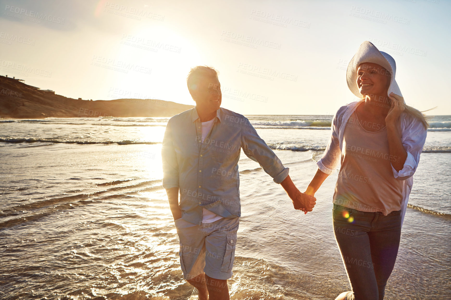 Buy stock photo Senior, happy couple and holding hands with beach sunset for support, love or bonding in nature. Man, woman or lovers walking with smile on outdoor summer holiday by water or ocean coast in sunshine