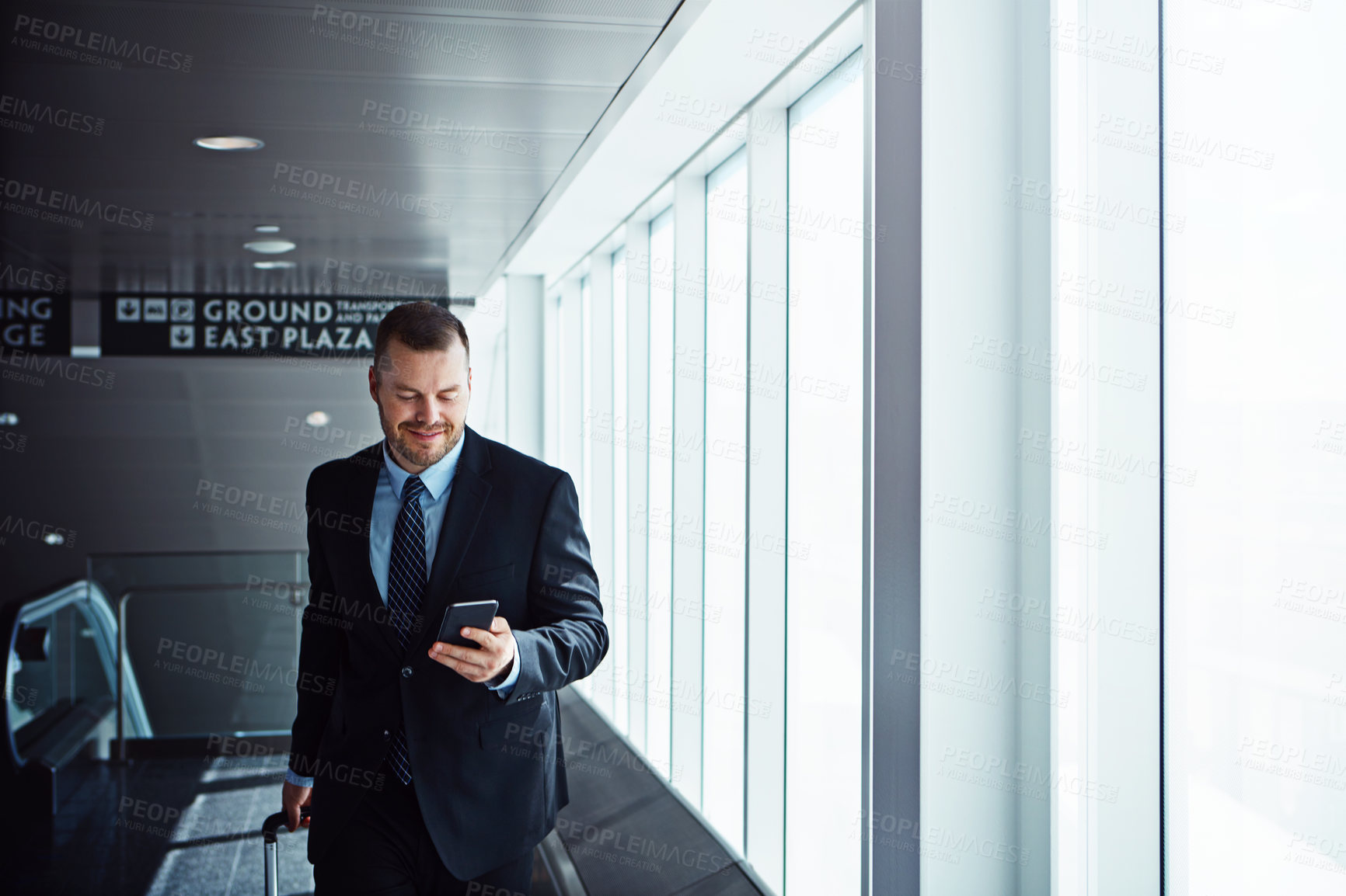 Buy stock photo Walking, news or businessman in airport with phone, luggage or suitcase for travel booking. Smile, entrepreneur or corporate worker texting on mobile app or social media on international flight 