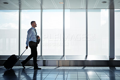 Buy stock photo Shot of a businessman walking down an airport corridor while on a business trip