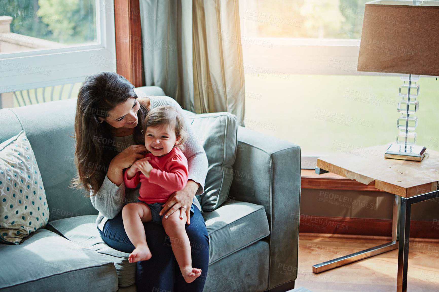 Buy stock photo Mother, child and playing or happy in home with relax, bonding or love with hug or fun together on sofa. Family, mom and daughter or kid with smile for trust, care or security in living room of house