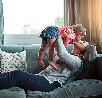 Buy stock photo Mom, kiss and lifting girl on sofa in home living room and relax, bonding and quality time together or mother, love and family happiness. Child, mommy and playing game on couch in house with smile