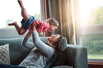 Buy stock photo Mom, happy and lifting girl on sofa in home living room and relax, bonding and quality time together or mother, love and family happiness. Child, mommy and playing game on couch in house with smile