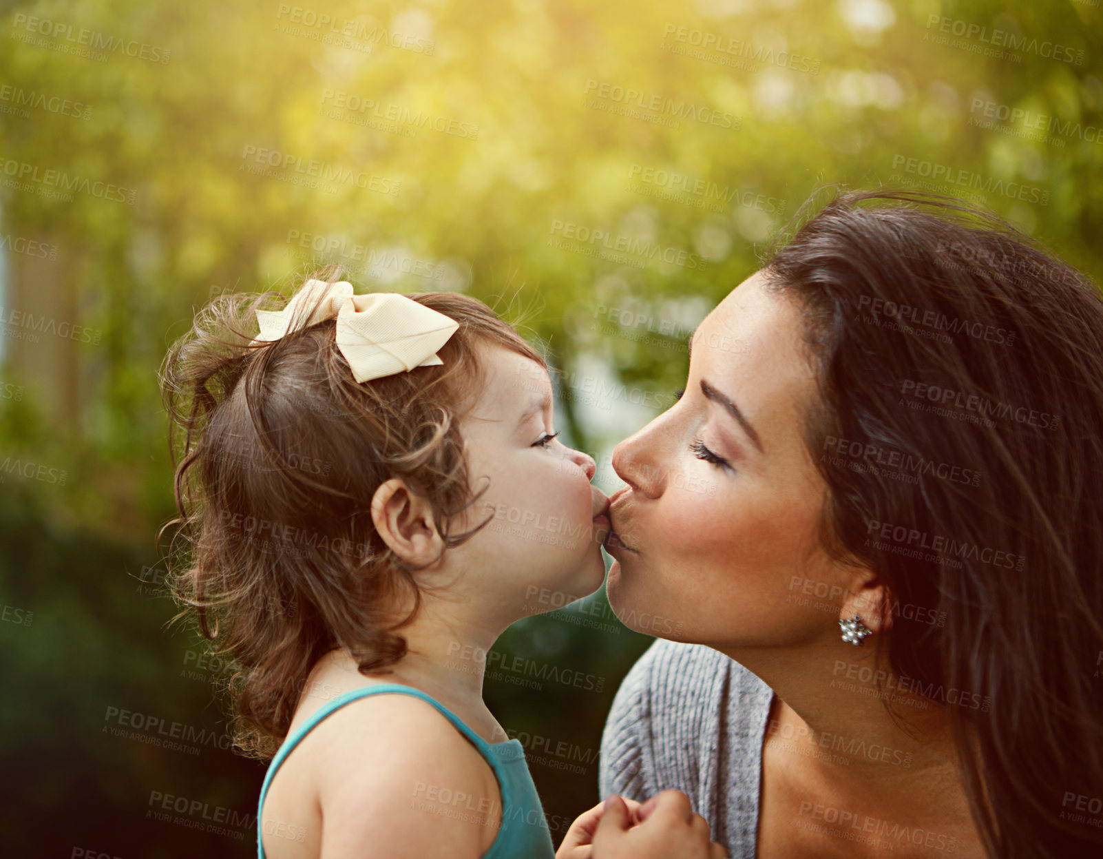 Buy stock photo Cropped shot of a mother giving her adorable little daughter a kiss outside