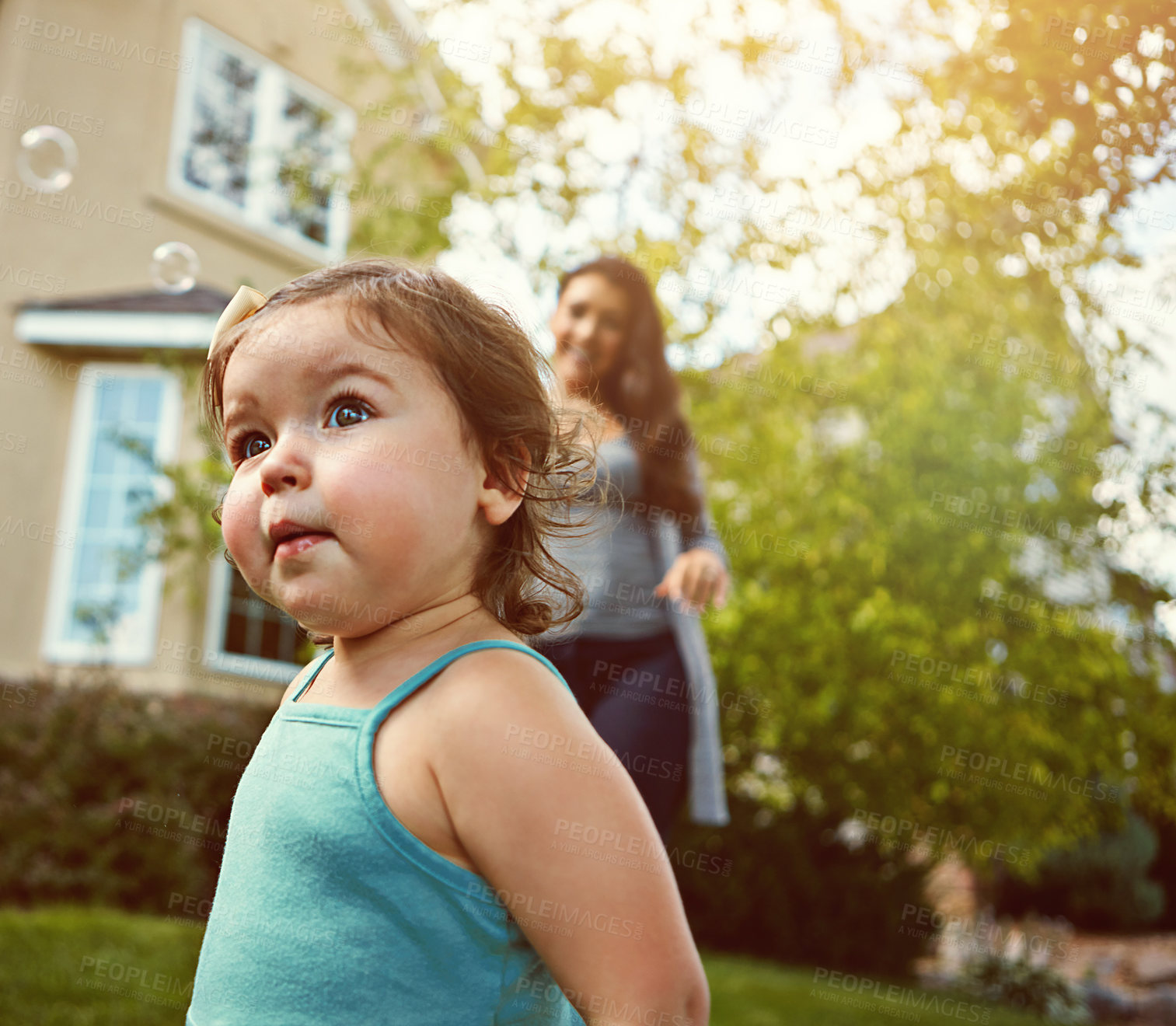 Buy stock photo Cropped shot of a mother and her adorable little daughter playing with bubbles outside