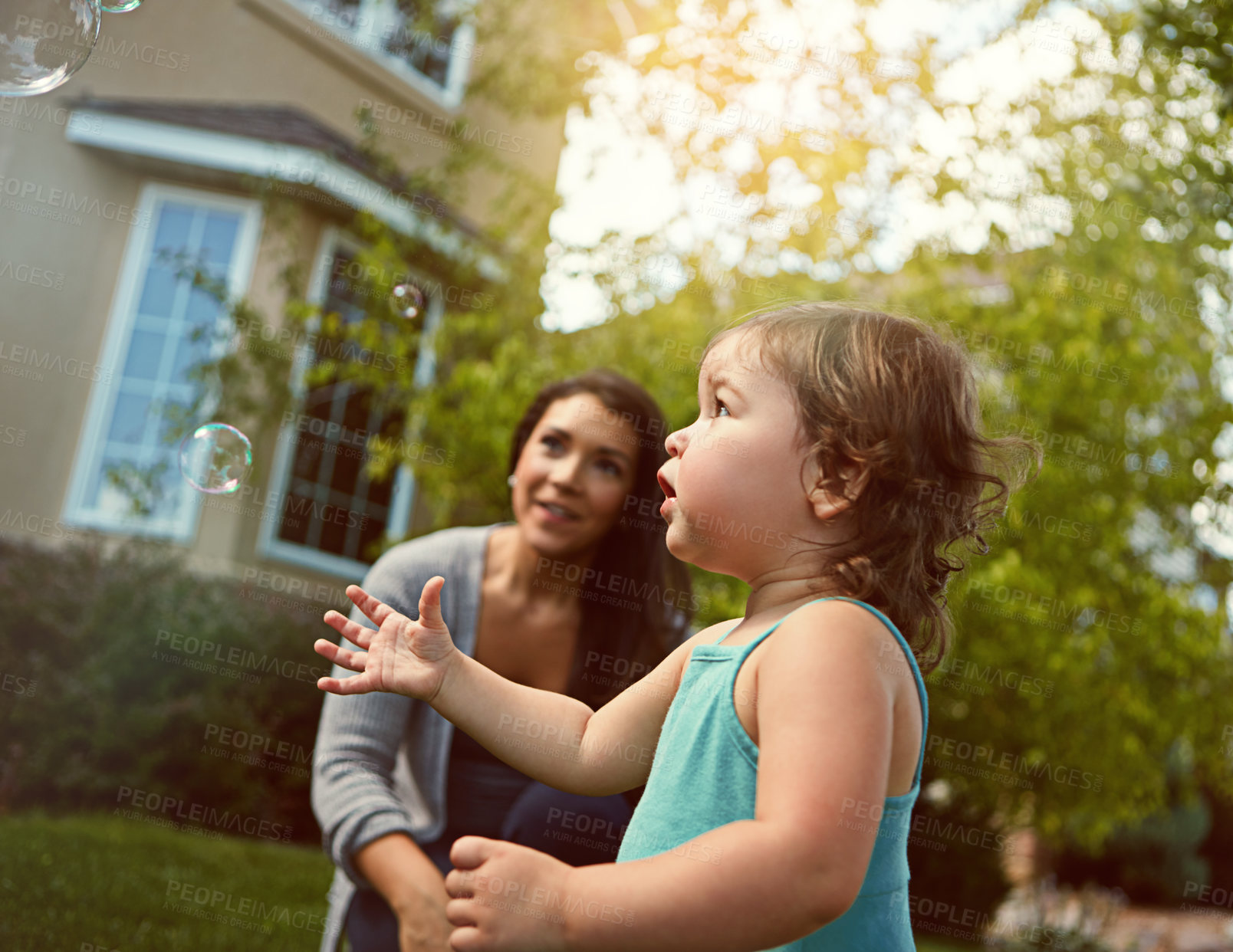 Buy stock photo Mom, girl and relax with bubbles in garden for games, playful and outdoor for bonding on grass at family house. Toddler, mother and daughter with soap, smile and love for connection on lawn in summer