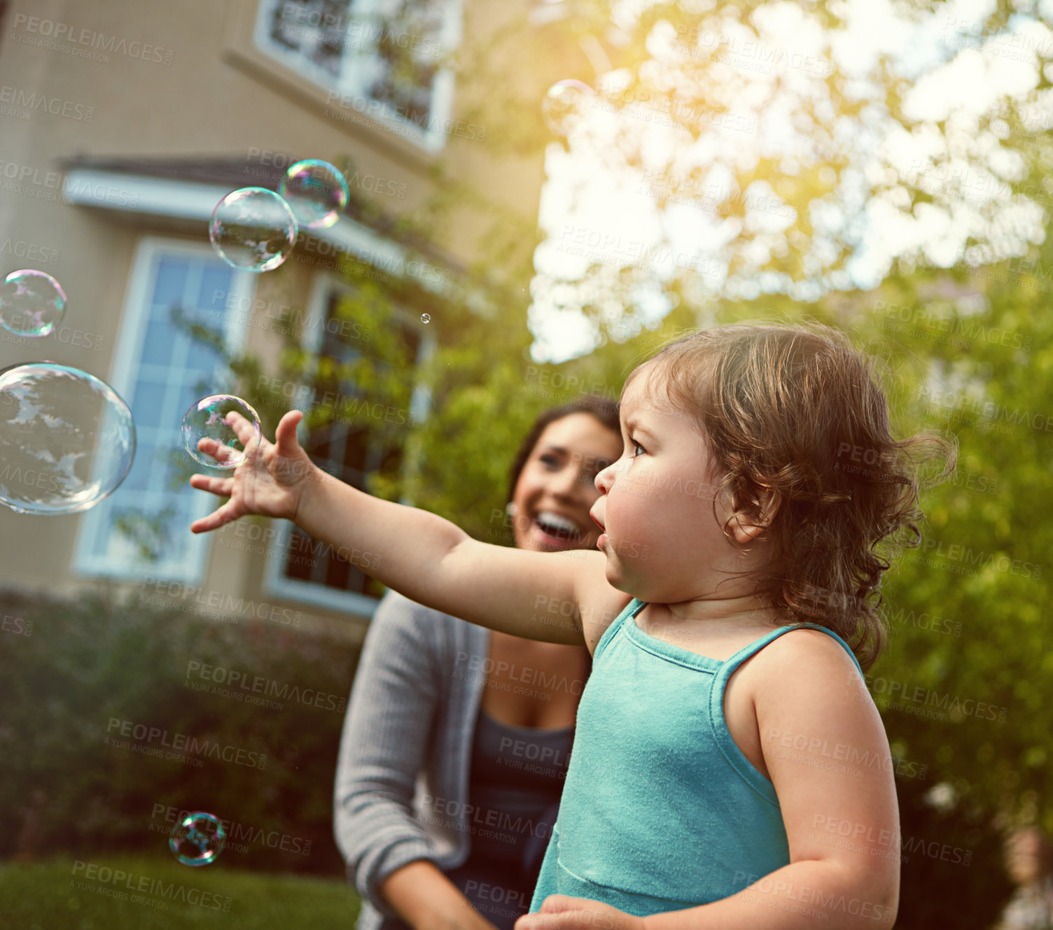 Buy stock photo Cropped shot of a mother and her adorable little daughter playing with bubbles outside