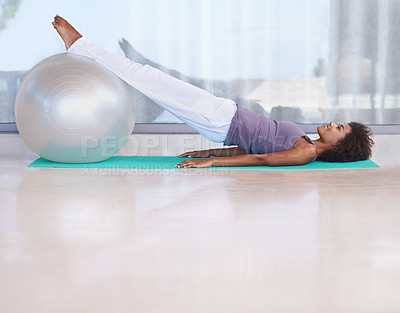 Buy stock photo Shot of an attractive young woman doing pilates with an exercise ball
