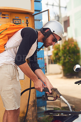 Buy stock photo Shot of a young tourist refueling his scooter at a gas station while exploring a foreign city