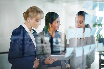 Buy stock photo Cropped shot of a group of businesswomen working together on a digital tablet in an office