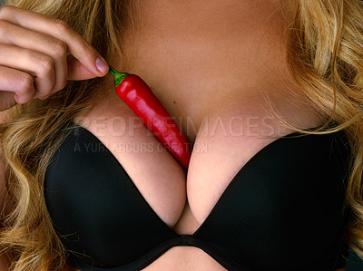 Buy stock photo Cropped studio shot of a young woman holding a red chili suggestively to her chest