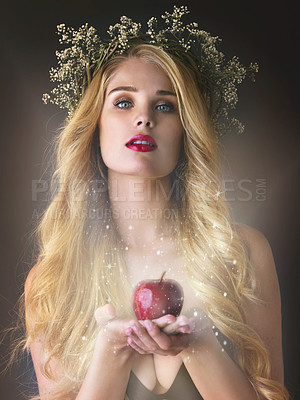 Buy stock photo Studio shot of a gorgeous young woman offering a magical red apple against a dark background