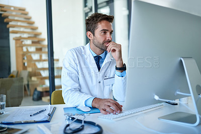 Buy stock photo Cropped shot of a young doctor working on a computer in his office