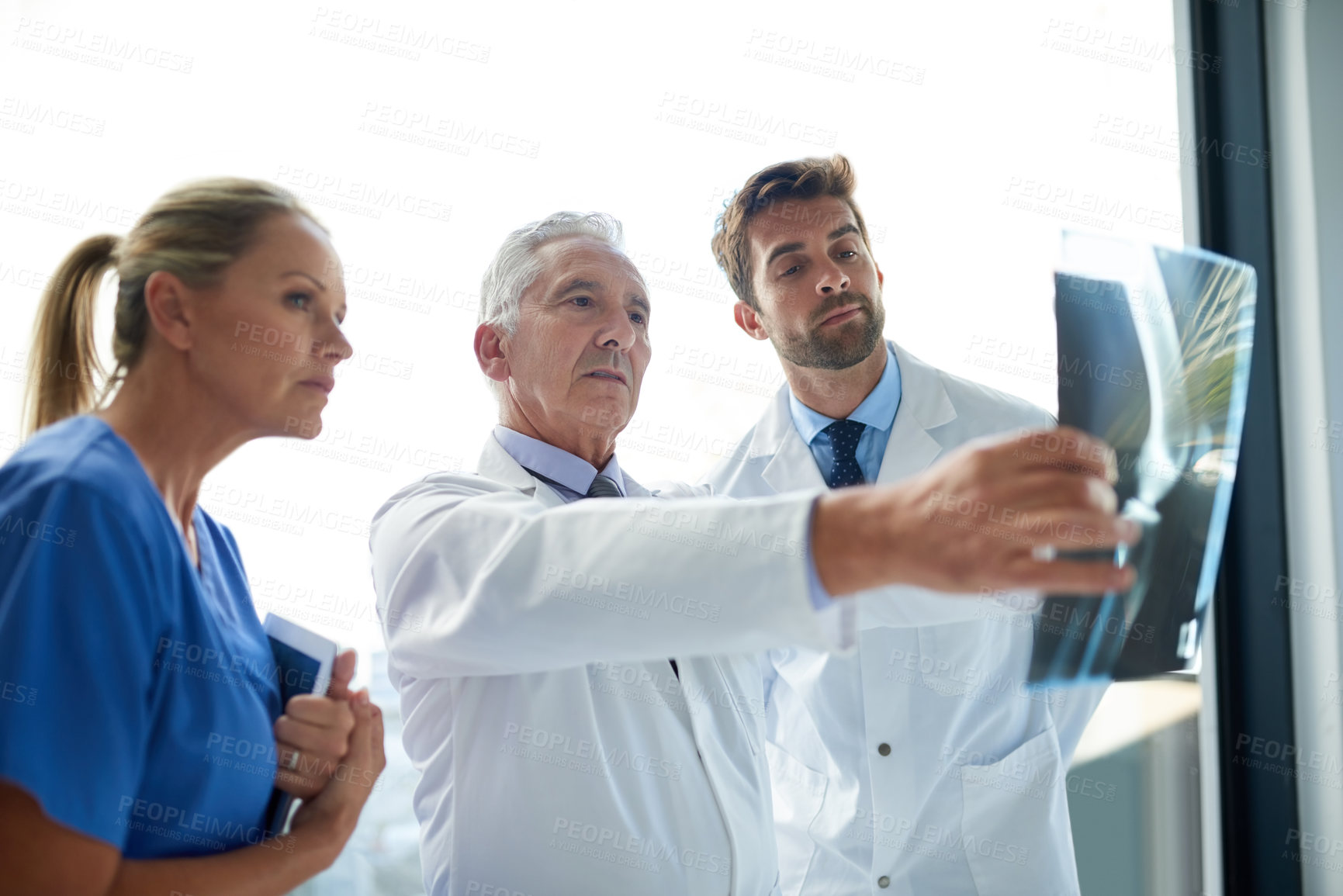 Buy stock photo Cropped shot of a group of medical practitioners examining an x-ray together