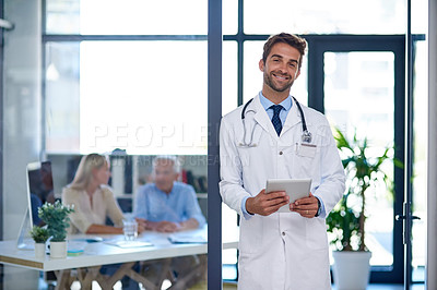Buy stock photo Portrait of a doctor using a digital tablet with two patients sitting in the background