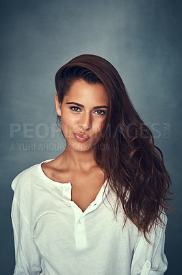 Buy stock photo Portrait of a beautiful young woman pulling a funny face against a gray background in studio