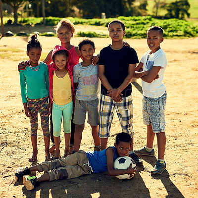 Buy stock photo Portrait of a group of children standing together with a soccer ball outside