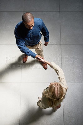 Buy stock photo High angle shot of two businesspeople shaking hands in an office