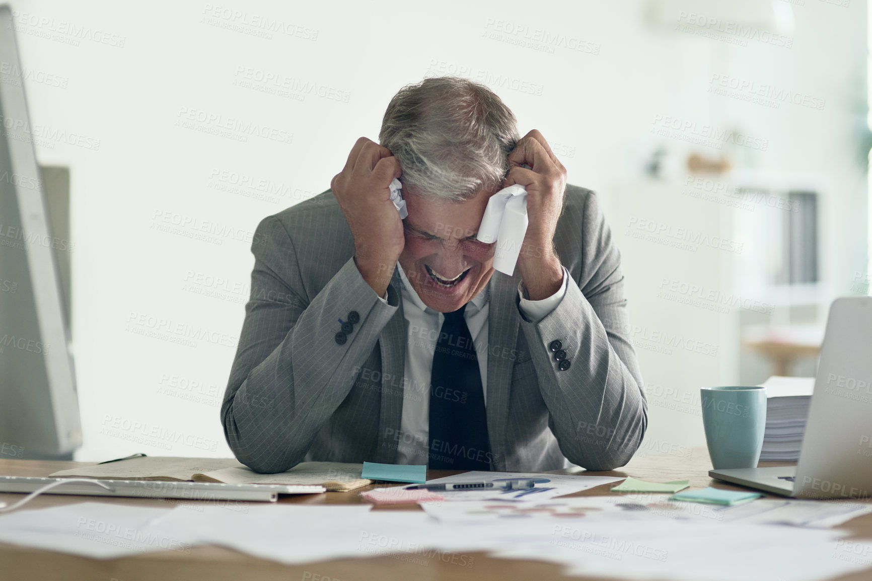 Buy stock photo Shot of a frustrated businessman crumpling up paperwork while sitting at his desk