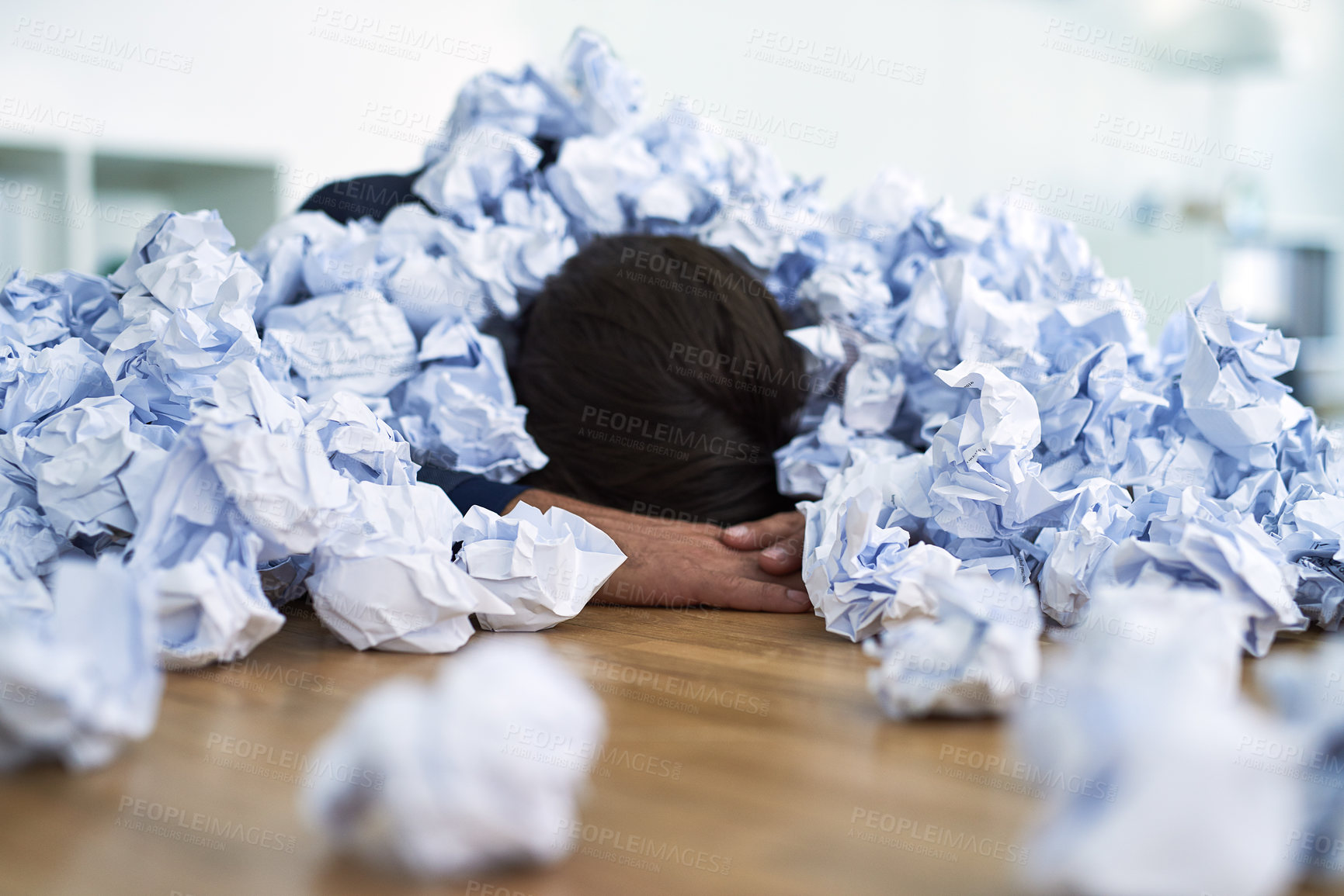 Buy stock photo Shot of an office worker passed out under a pile of crumpled up paperwork