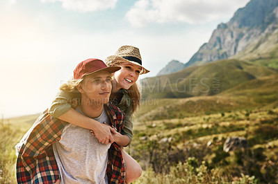 Buy stock photo Shot of a happy young couple enjoying a piggyback ride in nature