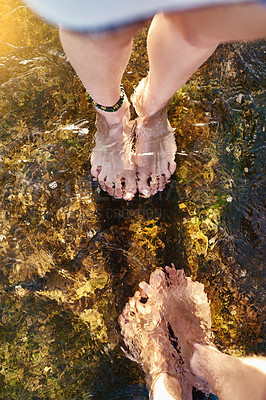 Buy stock photo Cropped shot of a couple standing in the cool waters of a stream