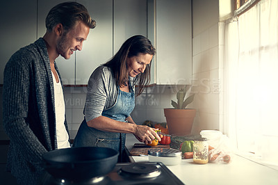 Buy stock photo Shot of a mother and her adult son cooking together in their kitchen at home