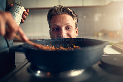 Buy stock photo Shot of young man watching his mother cooking on the stove in their kitchen at home