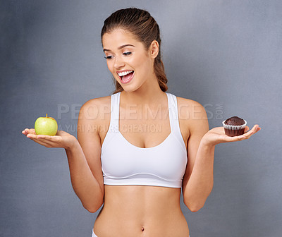 Buy stock photo Studio shot of a young woman choosing between healthy and unhealthy foods against a grey background