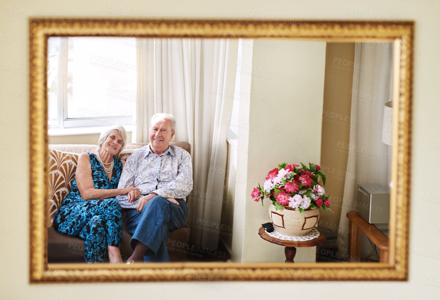 Buy stock photo Portrait of a happy senior couple relaxing on the sofa together at home reflected in a mirror