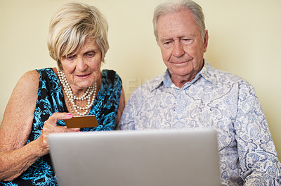 Buy stock photo Shot of a senior couple making a credit card payment on a laptop together at home