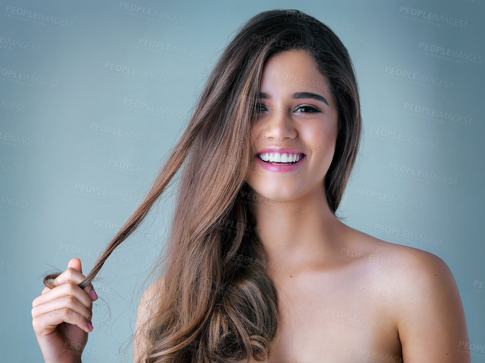 Buy stock photo Happy woman, portrait and hair with makeup for cosmetics, salon or spa on a blue studio background. Attractive, young female person or model with smile for haircare treatment, beauty or cosmetology