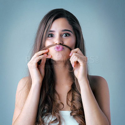 Buy stock photo Studio shot of a beautiful young woman playfully making a mustache with her hair